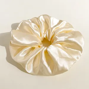 Dettaglio dell'elastico per capelli oversize in raso champagne con trama di seta liscia