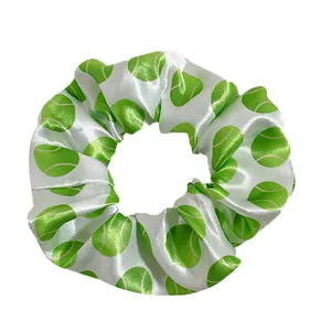Detail of white satin scrunchie with green tennis ball print and smooth silky texture