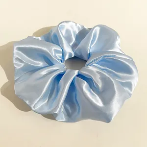 Dettaglio del tessuto in raso azzurro e della trama liscia di un elastico per capelli