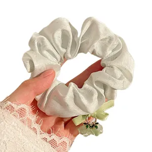Floral pendant scrunchie in light blue satin fabric with delicate bow detail