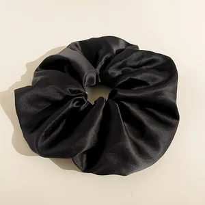 Dettaglio del tessuto in raso nero lucido e delle morbide pieghe sul maxi elastico