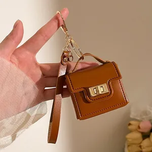 Dettaglio di un mini portachiavi a borsa in pelle marrone con cuciture fini dorate