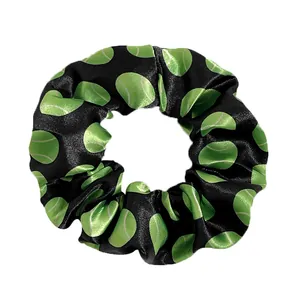 Detailed view of black satin scrunchie with green tennis ball print pattern