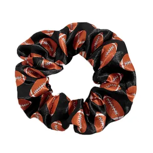 Detail of satin hair scrunchie with American football print on black fabric