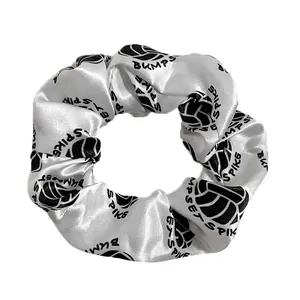 Detailed view of white satin volleyball scrunchie with Bump Set Spike print pattern