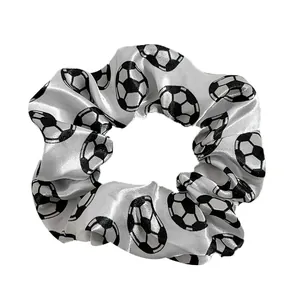 Detailed close-up of a white satin scrunchie featuring a classic black and white soccer pattern
