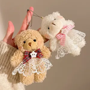 Close-up of cute plush teddy bear pendants with lace dresses and metal keychains
