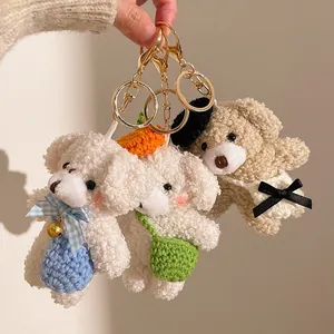 Three cute plush teddy bear keychains with bows and accessories in warm hand-held shot