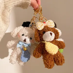 Close-up of cute plush teddy bear pendants with plaid bows and golden keychain hooks