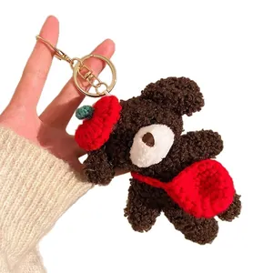Cute dark brown plush teddy bear keychain with a red knit hat and crossbody bag