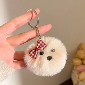 Detail van de zachte beige pluche sleutelhanger met puppygezicht en rode geruite strik