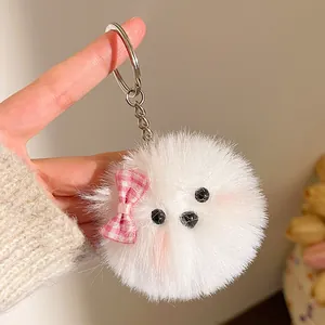 Gedetailleerde close-up van een witte pluchen puppy sleutelhanger met roze strik