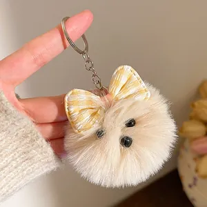 Detail van witte pluche honden sleutelhanger met gele geruite strik voor tas decoratie