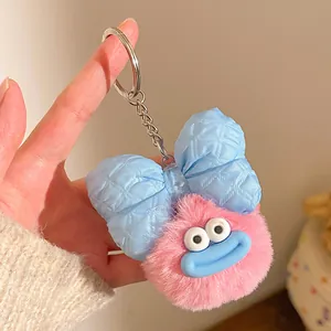 Gros plan d'un porte-clés monstre en peluche rose avec un grand nœud bleu