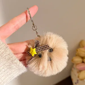 Detail van een schattige beige pluche hamster sleutelhanger met bruine geruite strik