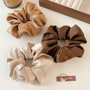Vue détaillée de trois chouchous en satin de soie aux tons crème, caramel et café