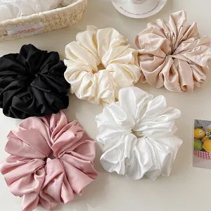 Close-up of oversized satin scrunchies in five elegant neutral colors in a basket
