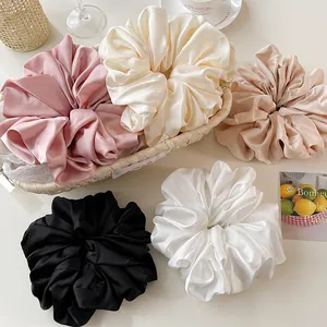 Detailed close-up of oversized satin scrunchies in five elegant neutral colors in a basket