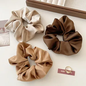 Lot de trois chouchous en satin crème, caramel et marron foncé avec texture soyeuse