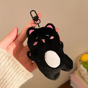Close-up of cute black plush cat keychain with pink embroidery held in hand