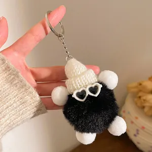 Gros plan d'un porte-clés en peluche noire avec bonnet blanc et lunettes en forme de cœur