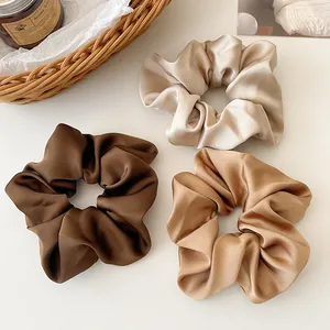 Détail de chouchous en satin marron et crème avec une brillance soyeuse élégante