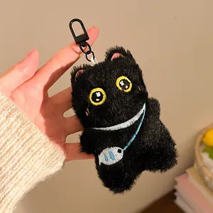 Close-up of black plush cat keychain with yellow eyes and a small fish charm detail