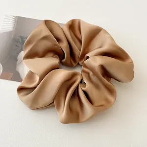 Gros plan d'un chouchou en satin marron champagne montrant sa texture brillante et ses plis
