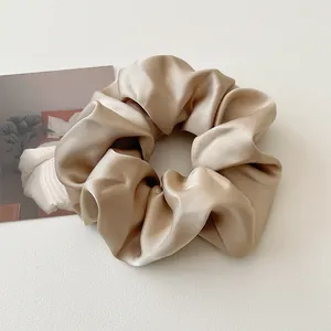 Gros plan sur un chouchou en satin champagne avec texture en soie brillante sur blanc