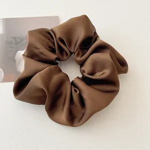 Détail d'un chouchou en satin marron foncé élégant avec texture lisse et plis doux