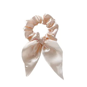 Detail of champagne pink satin scrunchie with long ribbons and silky fabric texture