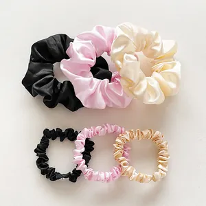 Detail of silk satin scrunchies set in black, pink and champagne colors with two sizes