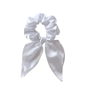 Detail of elegant white satin scrunchie with long bow streamers and glossy silk texture
