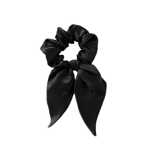 Close-up of black satin bow scrunchie with long ribbons and elegant silk texture