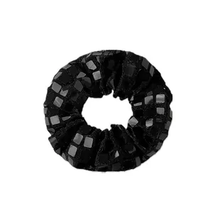 Détail de paillettes carrées effet miroir sur chouchou noir avec reflets disco brillants