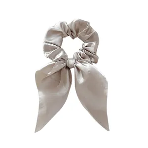 Detail of silk satin scrunchie with long bow ribbons in elegant champagne color
