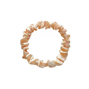 Detail of premium champagne satin hair scrunchie showing smooth texture and soft folds