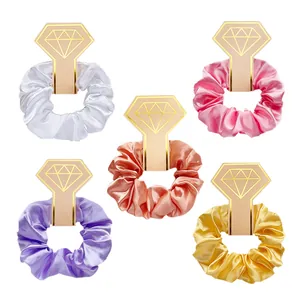 Detail van 5 satijnen haarelastiekjes op diamantvormige cadeaukaarten in pastelkleuren