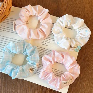 Detailed view of striped and floral scrunchies with cute woven labels on wooden table