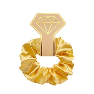 Detailweergave van gele satijnen scrunchie op een decoratieve diamantvormige kaart