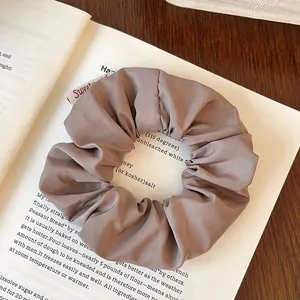 Close-up of deep khaki matte scrunchie with Sweet embroidery label on vintage book