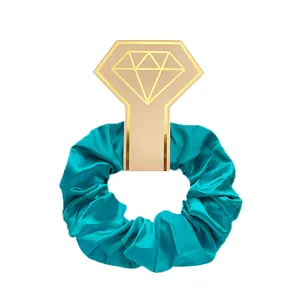 Detailweergave van een cyaan satijnen scrunchie op een roze diamantvormige geschenkkaart