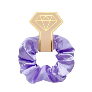Detail van een paarse satijnen haarscrunchie op een diamantvormige roze kaarthouder