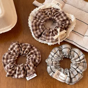 Detailed shot of three plaid hair scrunchies with lace trim and soft cotton fabric texture