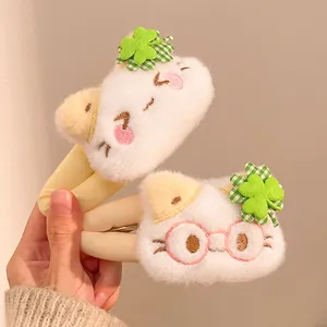 Detailed close-up of white plush cat hair clips with green clover and embroidery detail