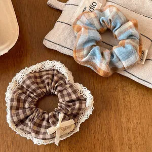 Close-up of plaid scrunchies with white lace trim and cute bow on a wooden background