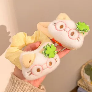 Macro view of cute plush cat head hair scrunchie with lucky clover detail