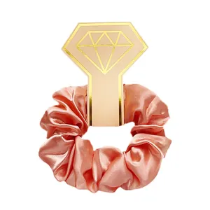 Detailweergave van een satijnen scrunchie in champagne op een gouden kaarthouder