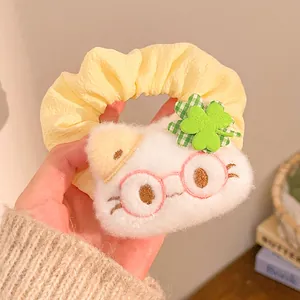 Detail of yellow scrunchie with plush white cat head and green clover ornament
