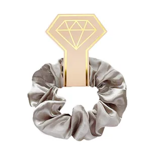 Detail van champagne satijnen scrunchie op een roze diamantvormige geschenkkaart
